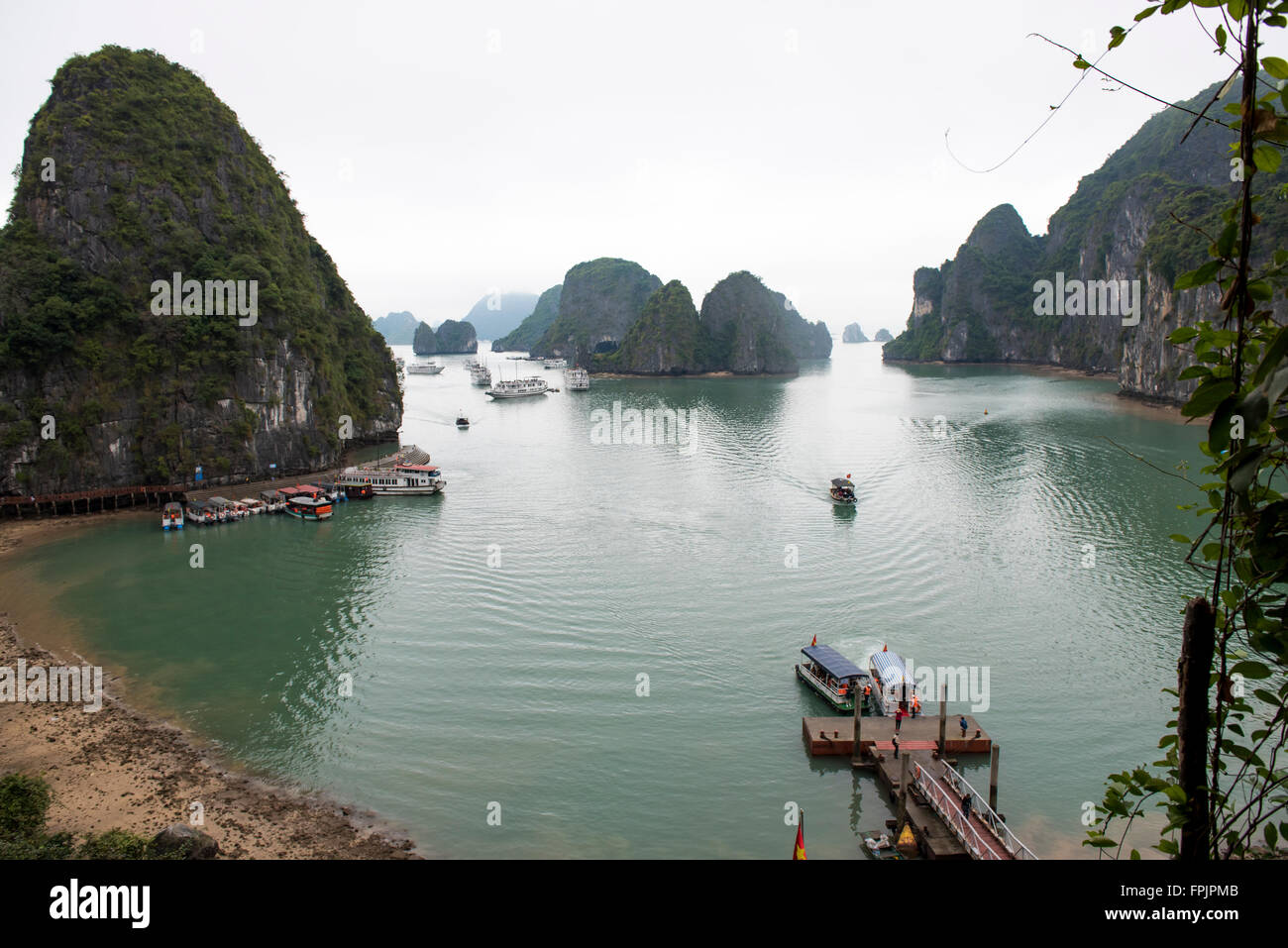 Tourist boats clustering around the harbour to Hang Sung Sot cave.  View of the limestone islands, mist and calm sea Stock Photo