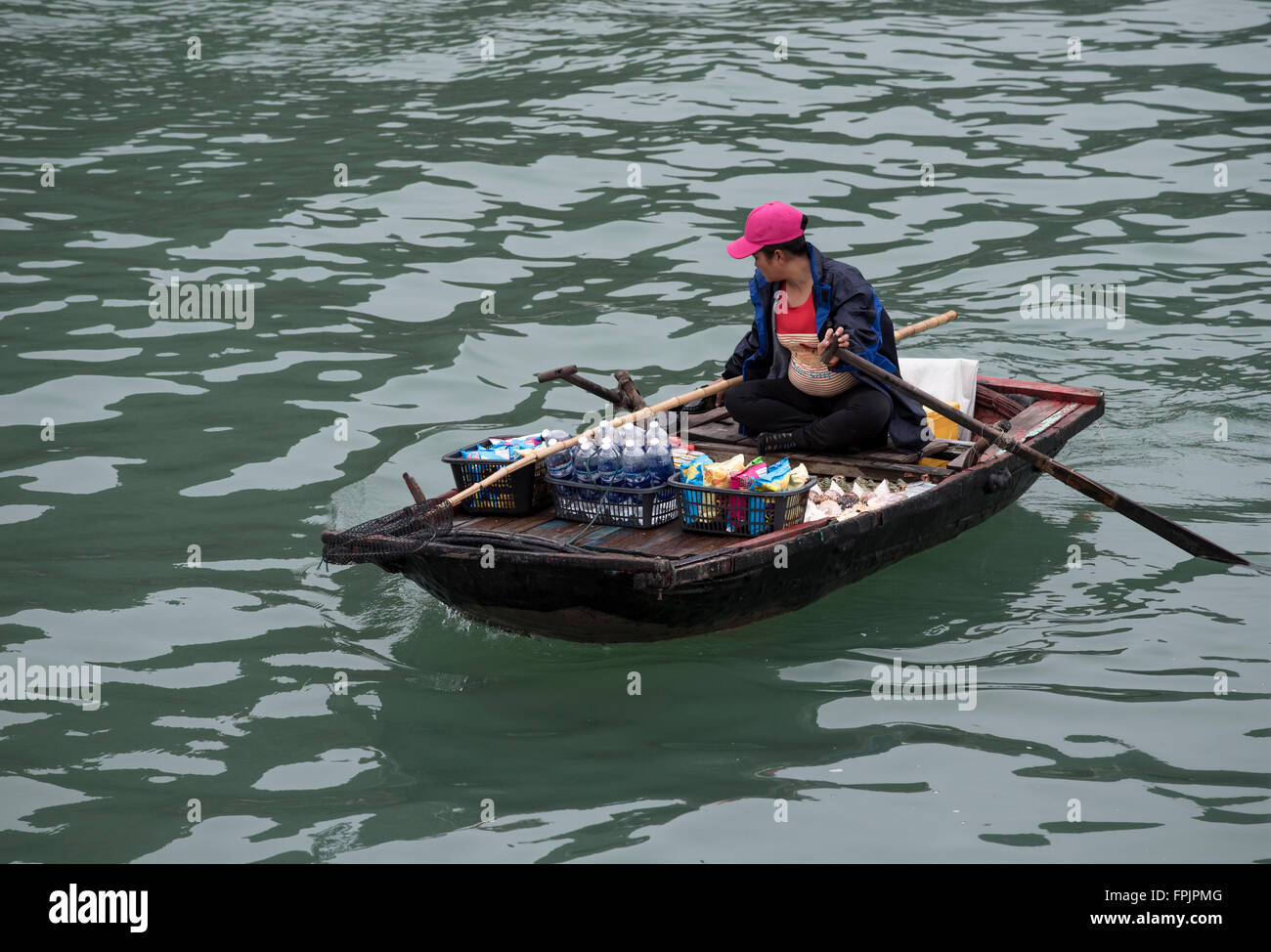 Halong Bay, Vietnam  A Vietnamese woman in her rowing boat selling drinks and snacks to tourists in the cruise ships Stock Photo