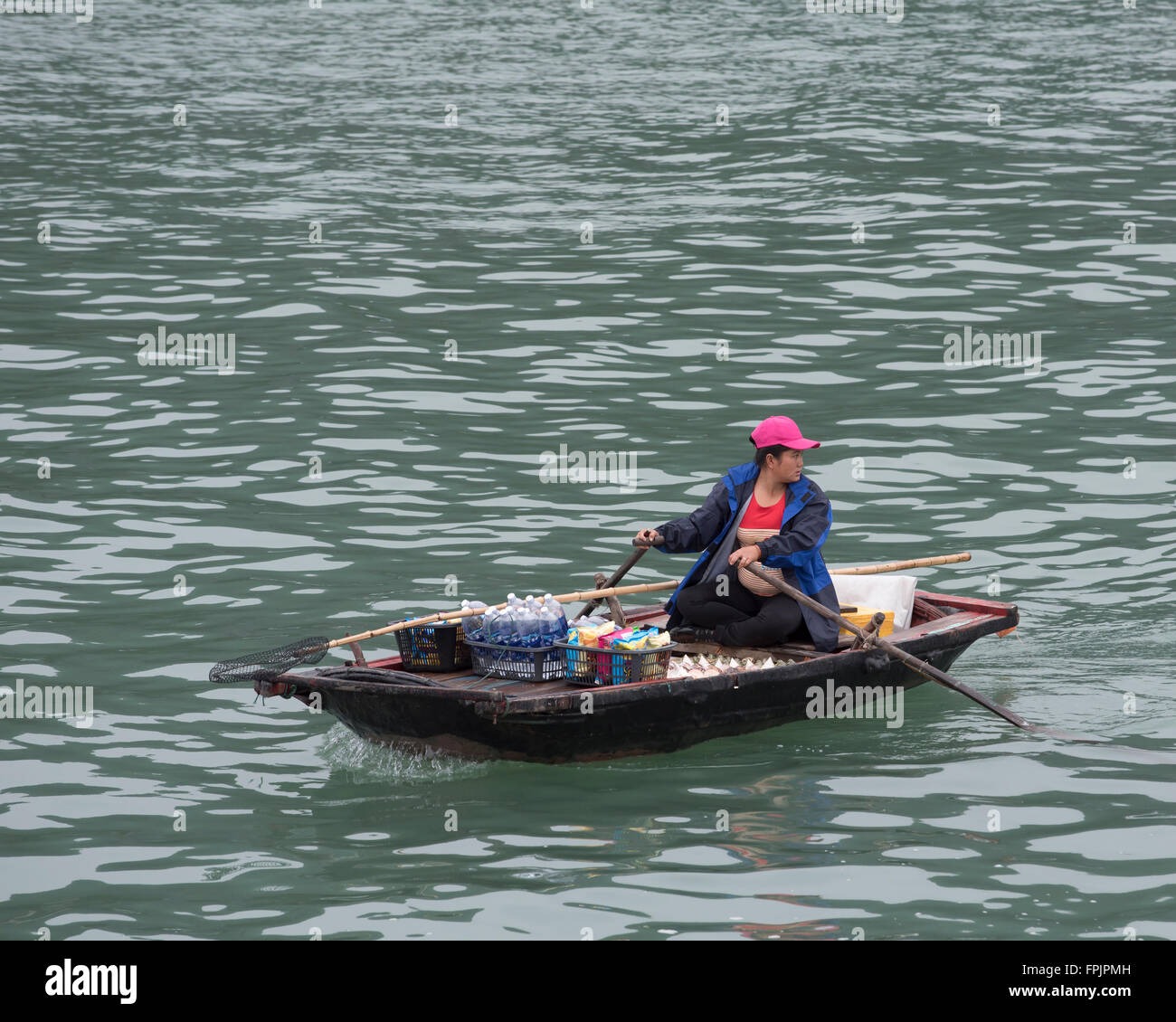 Halong Bay, Vietnam  A Vietnamese woman in her rowing boat selling drinks and snacks to tourists in the cruise ships Stock Photo