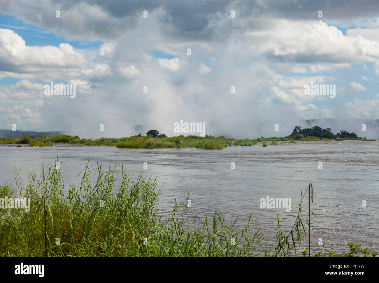 View over the Zambezi River towards Mosi oa tunya, the 'smoke that thunders', the spray rising from the Victoria Falls, Zambia. Stock Photo