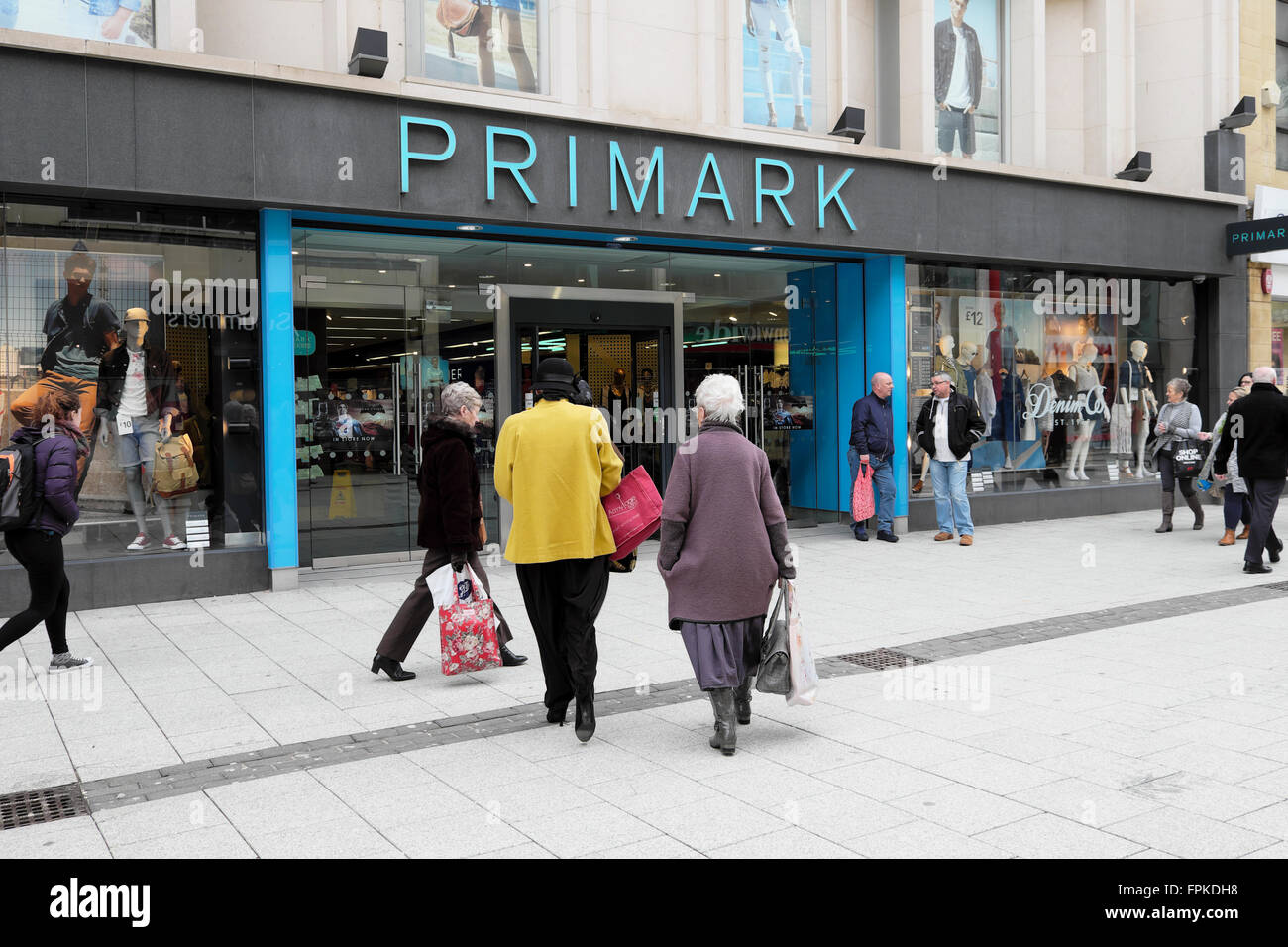 Shoppers rear back view of women outside the entrance of a Primark store sign on Queen Street in Cardiff City Centre Wales UK  KATHY DEWITT Stock Photo