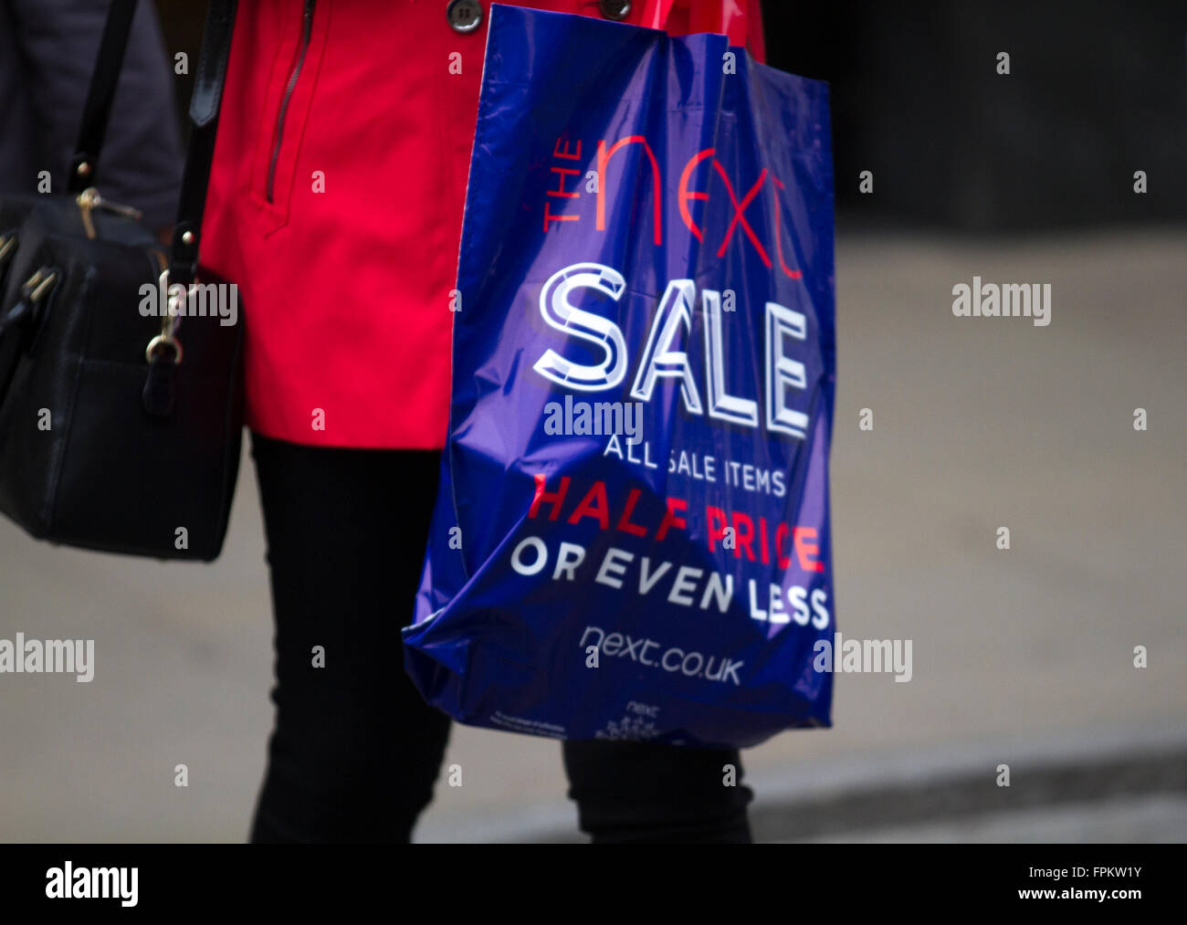 Woman carrying goods, half price items in a blue shopping bag,  purchased from Next clothing shop; Sale Event in Chester, Cheshire, UK 19th March, 2016. Stock Photo