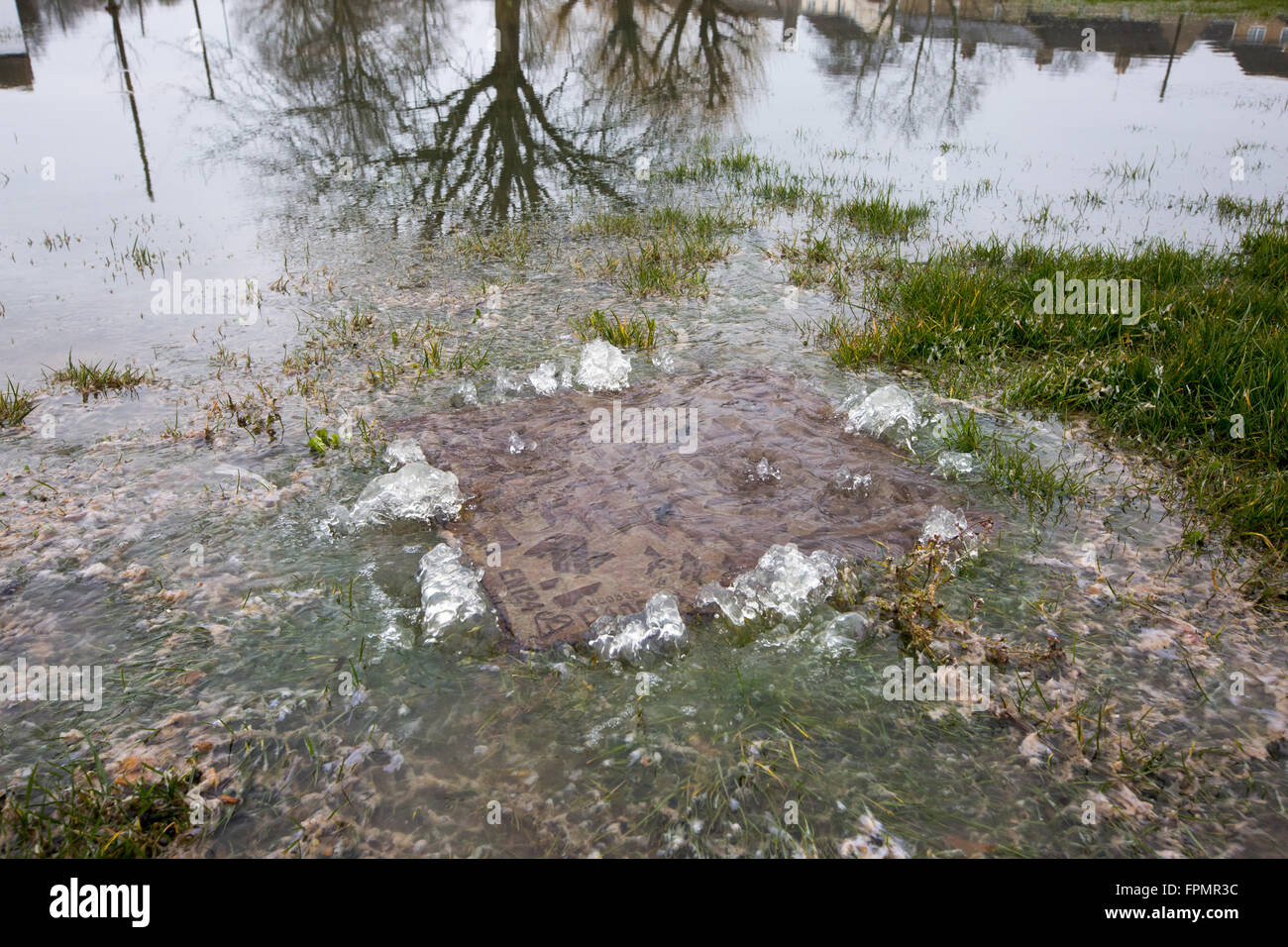 Flooded water coming through a drain,man hole cover. Stock Photo