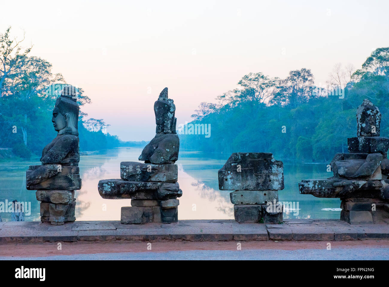 Sunset on the causeway to the South Gate of Angkor Thom with Gods and demons pulling on a giant snake leading to  the city Stock Photo