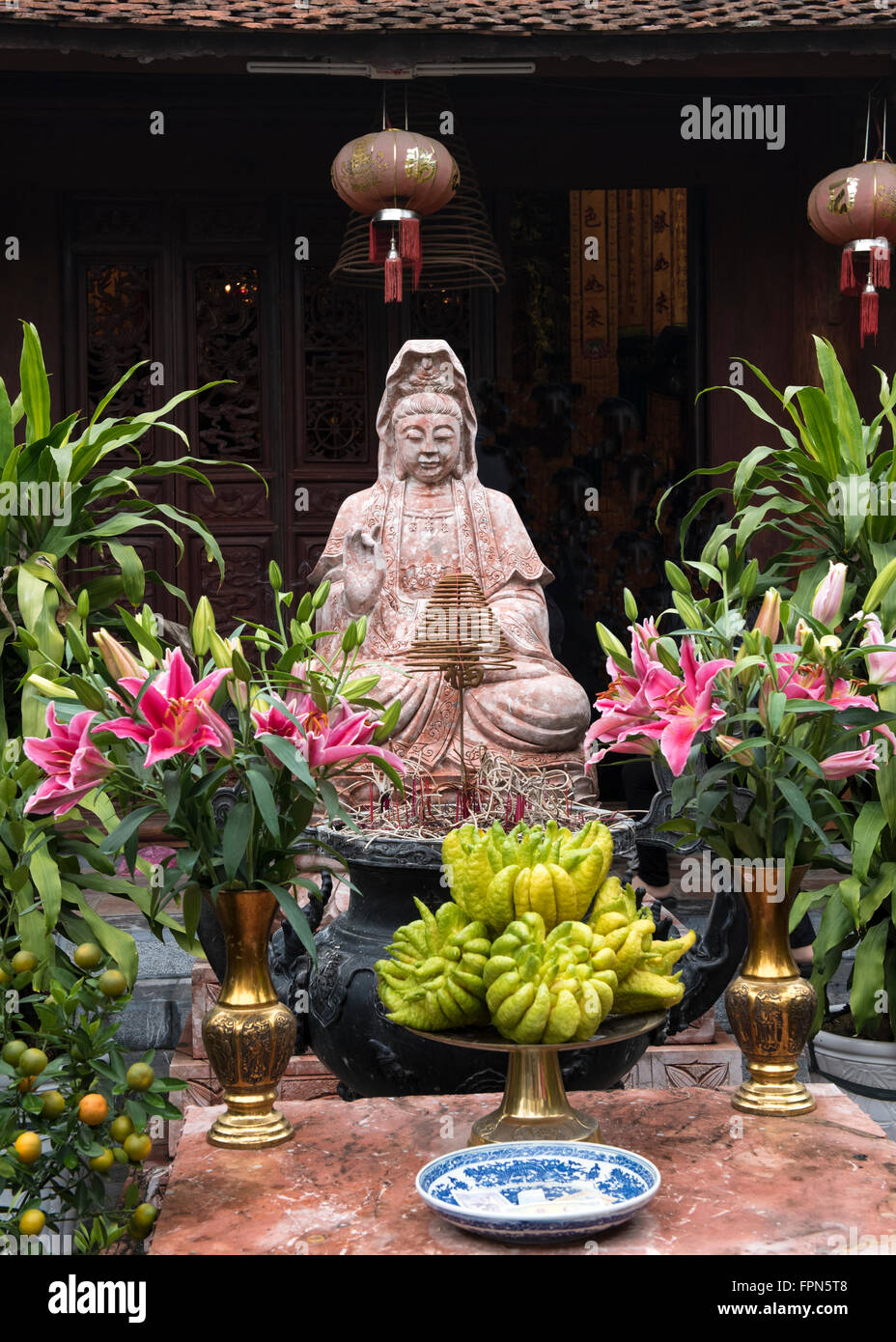 Buddha in a Vietnamese temple with offerings including flowers and the