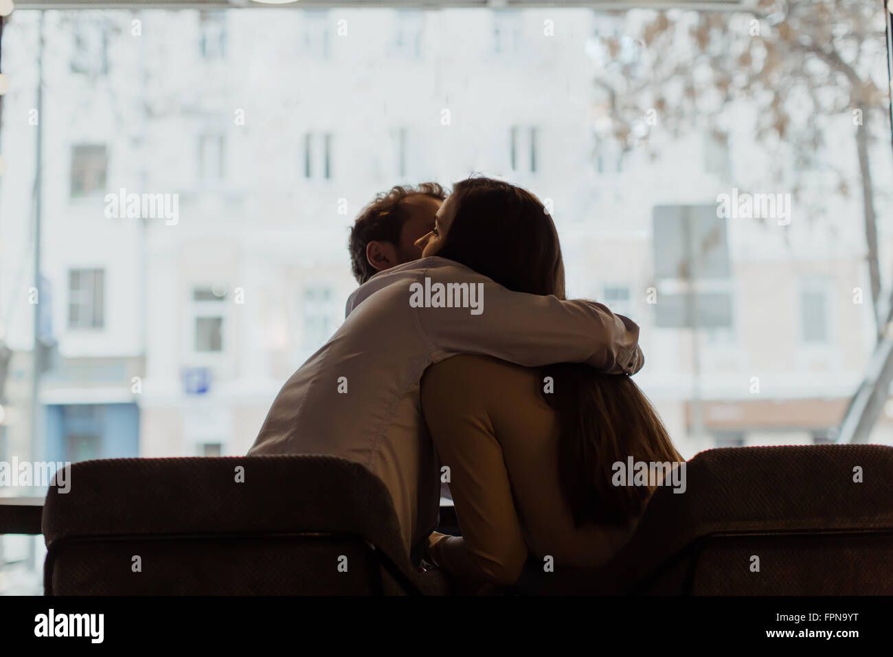 Couple hugging against the window, silhouette Stock Photo