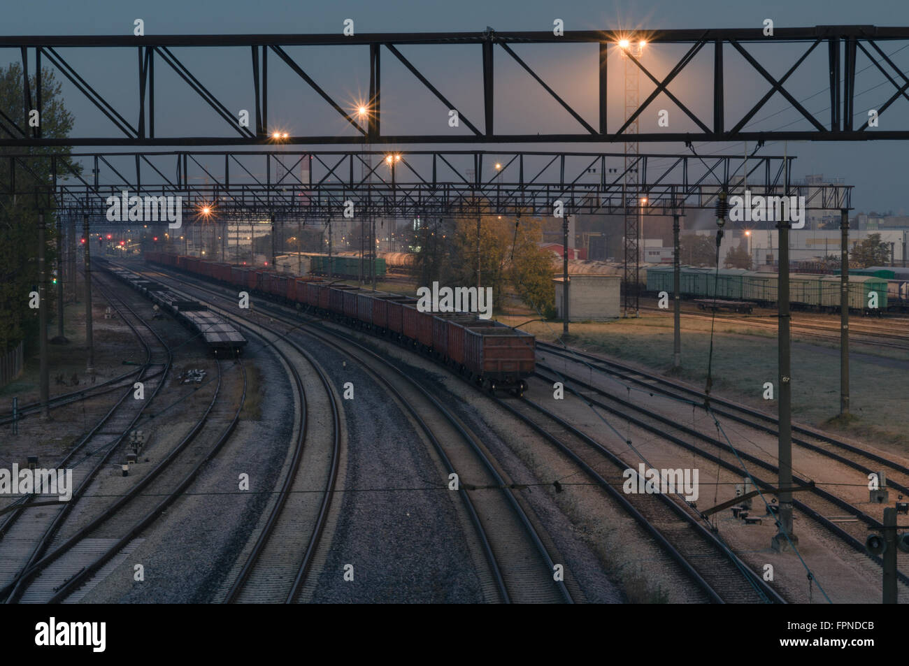 Illuminated cargo train station by night. Curve platform with containers Stock Photo
