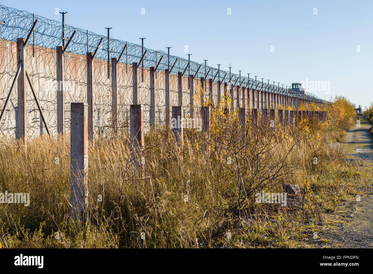 Prison wall and sharp wire barbs coiled in autumn time Stock Photo