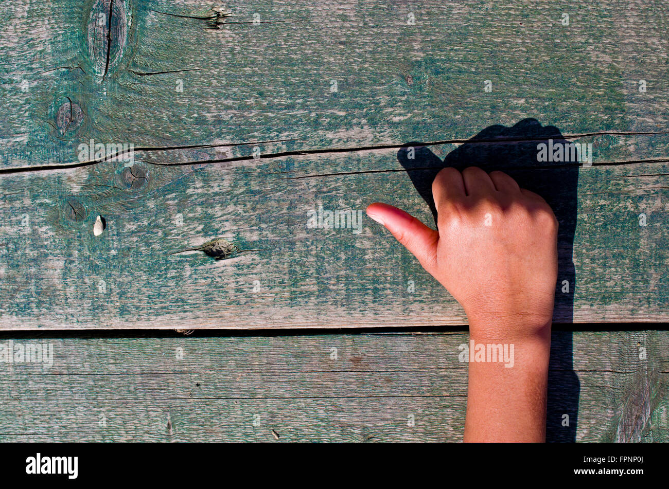 a hand tells us the right number, one, two, three, four, five out of an aged wooden table Stock Photo