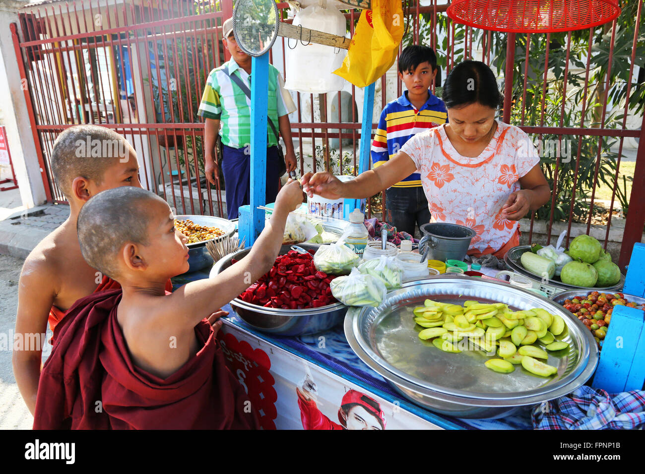 Young monks at the Atum Ash Monastery buying food from a street vendor, Mandalay, Myanmar (Burma) Stock Photo
