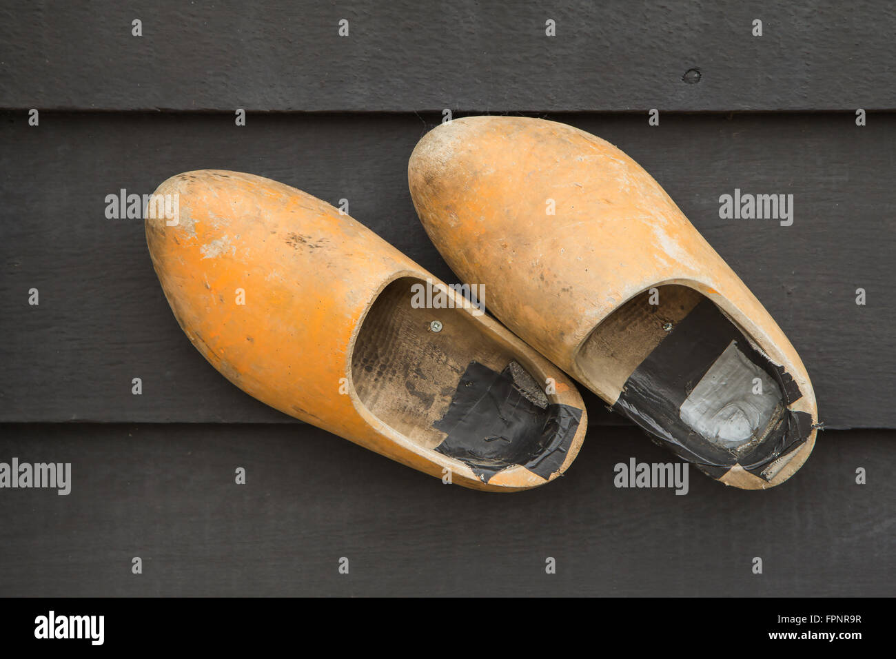A pair of old wooden clogs on a wooden wall. Stock Photo