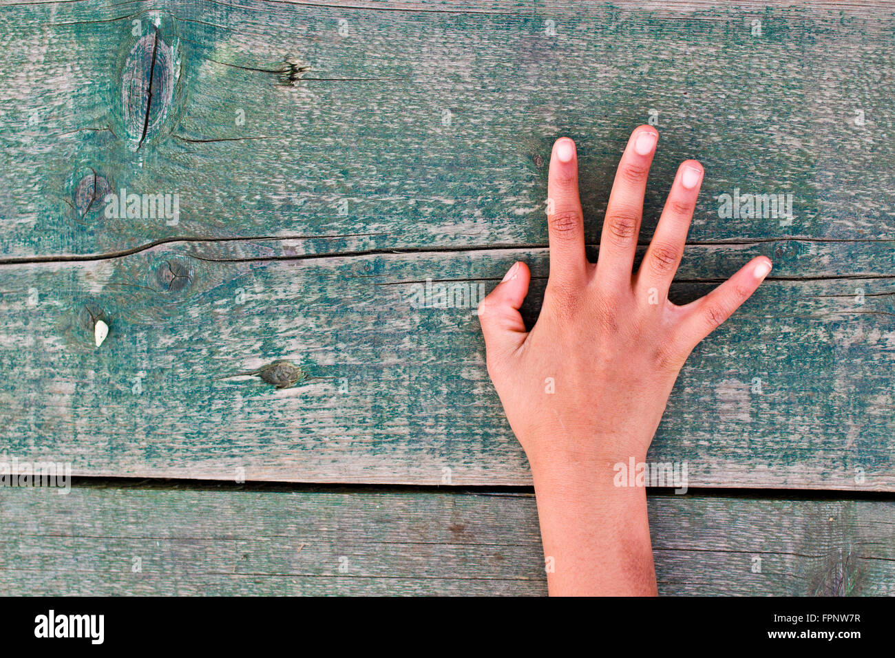 a hand tells us the right number, one, two, three, four, five out of an aged wooden table Stock Photo