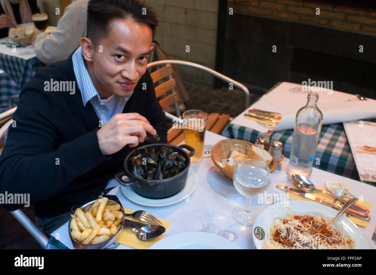 Asian tourist tasting the typical dish of Brussels: mussels and frites. Belgium. Rue des Bouchers. A couple in one of the many r Stock Photo
