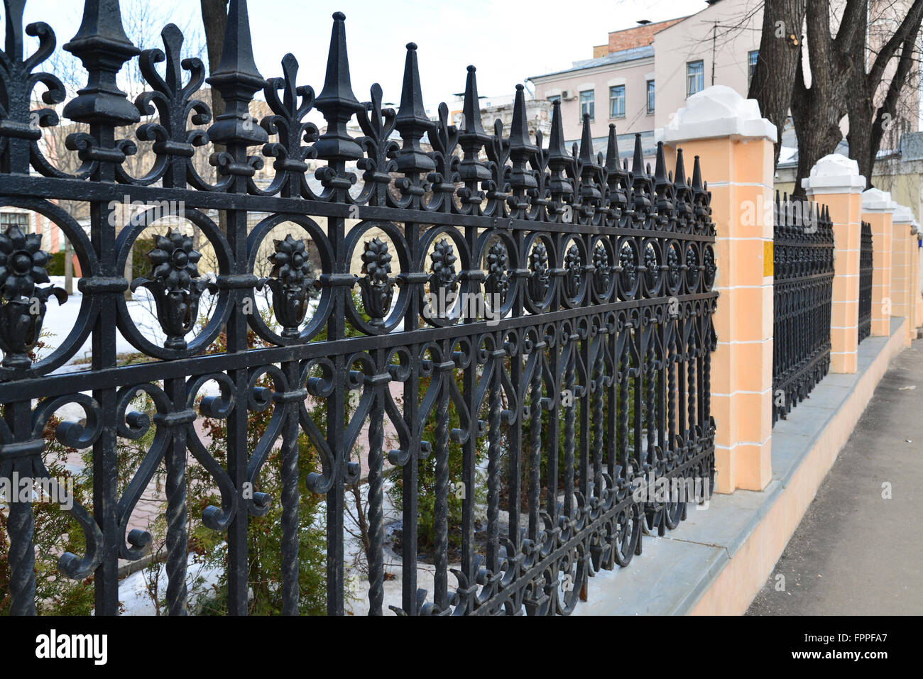 Black painted iron fence mounted at  small wall of brickstones Stock Photo