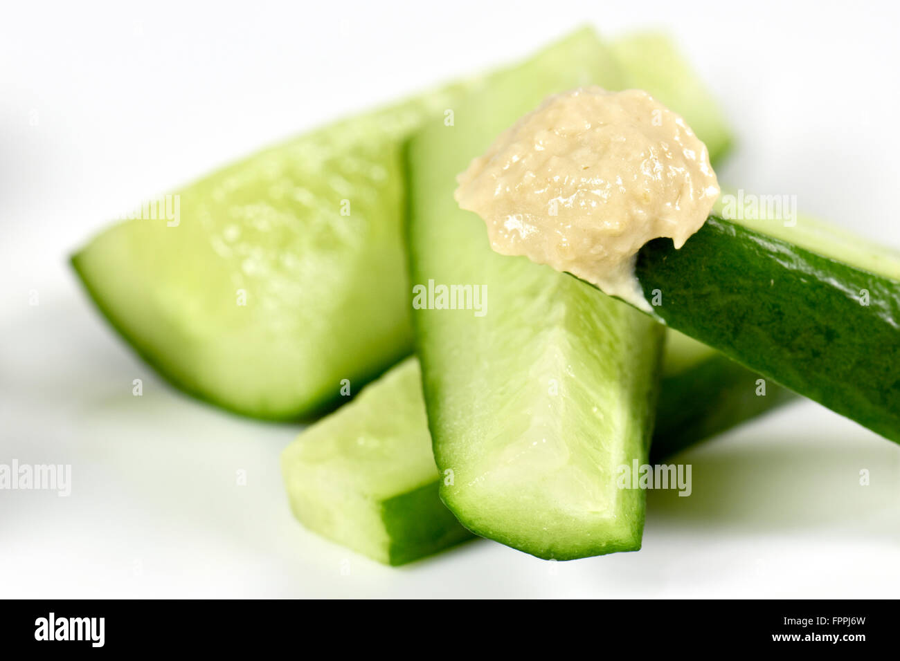 Cucumber slices with hummus on white plate Stock Photo
