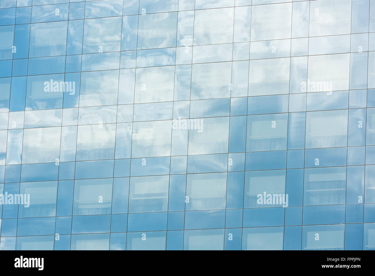 blue sky and clouds reflected in windows of modern office building ...
