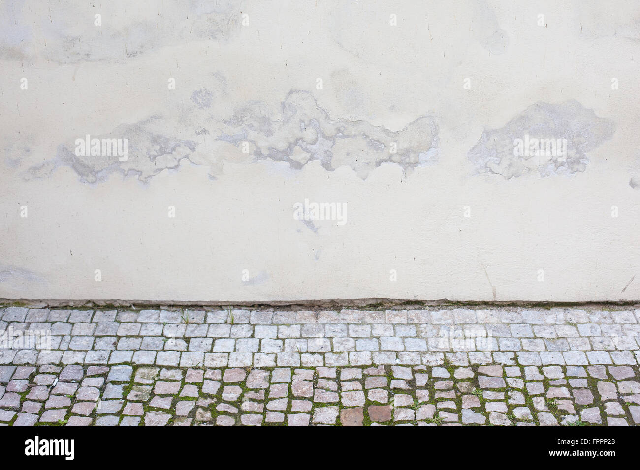 Weathered stucco wall and cobblestones of a church in Prague Stock Photo