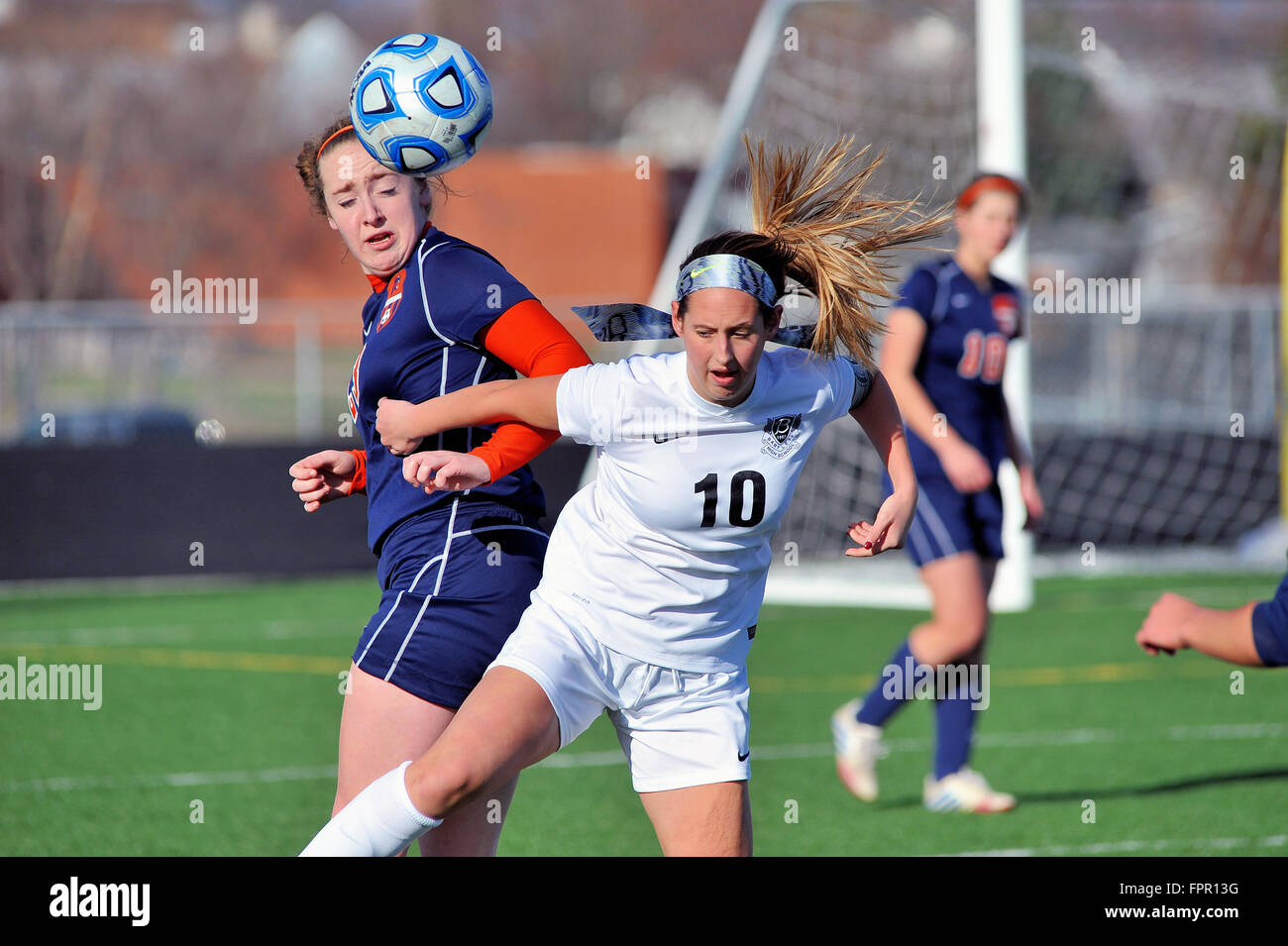 Pair of high school players battling to control the ball following a contested header duel between the two. USA. Stock Photo