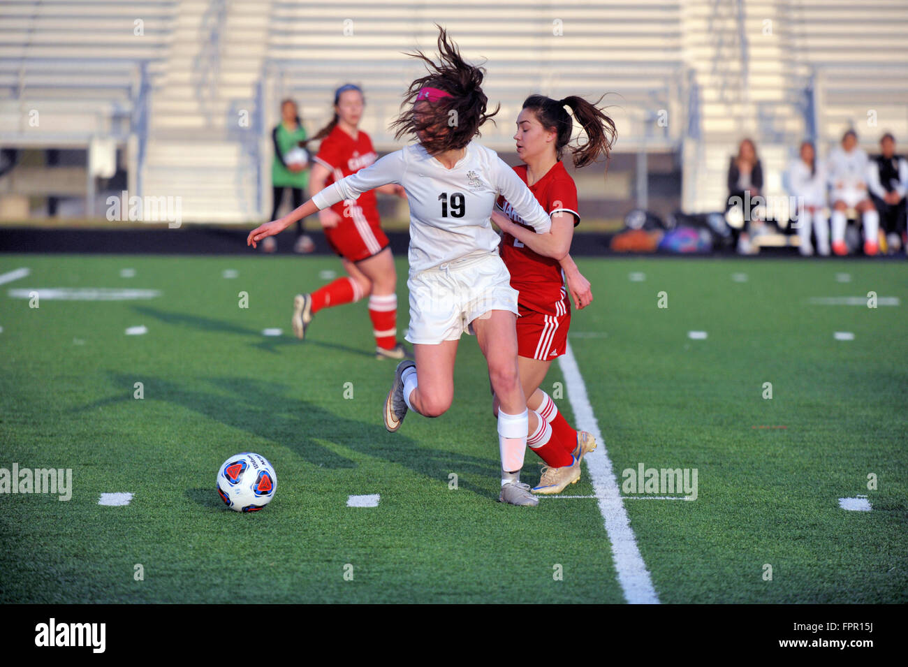 High school player controlling the ball as she cuts across the middle of the filed while looking for a teammate passing target. USA. Stock Photo