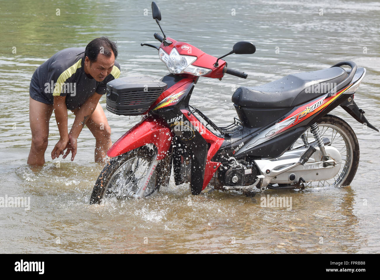 Man washing his motorbike in the Mekong River Laos Stock Photo