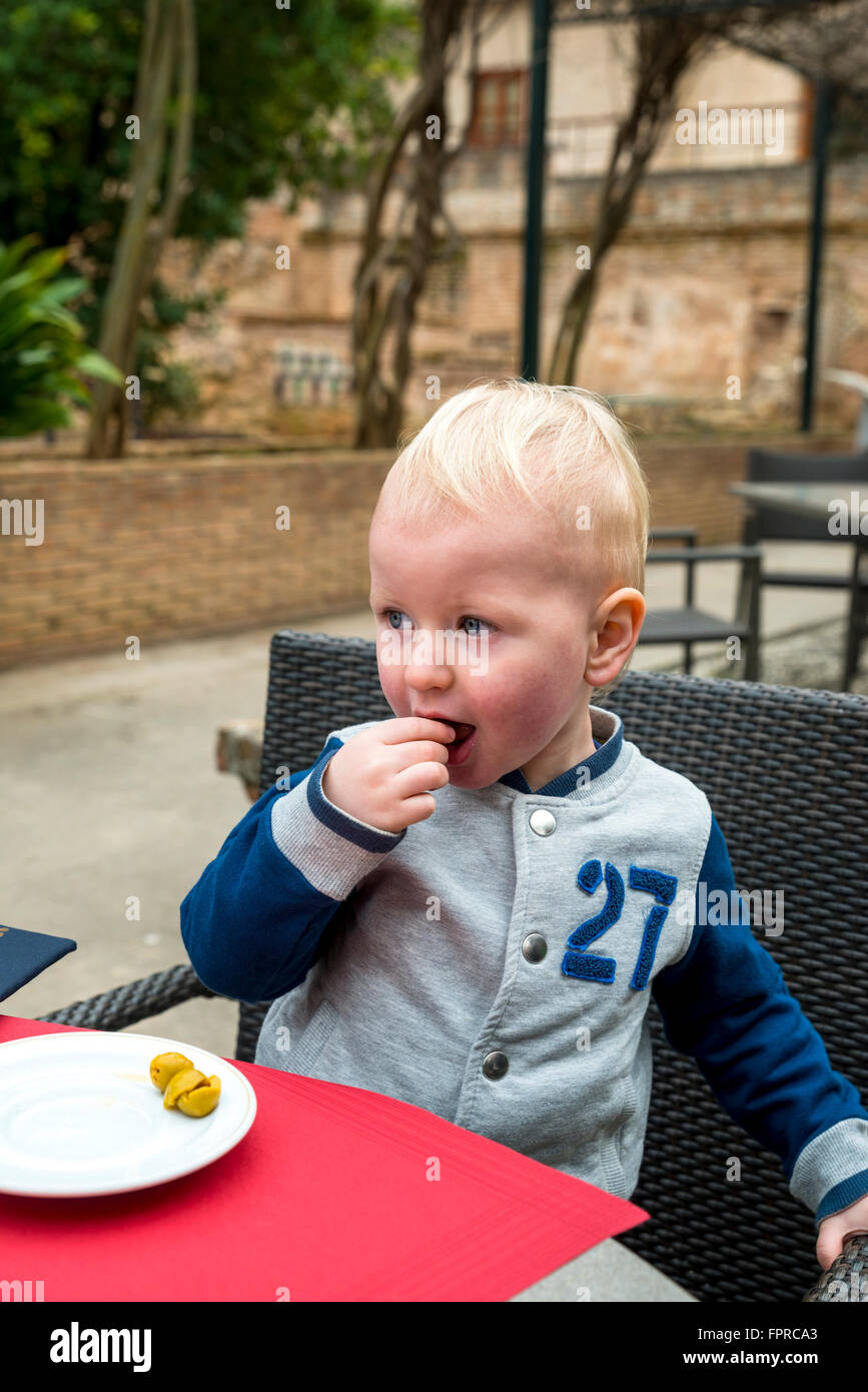 2 year old boy eating green olives, Alhambra, Granada, Spain, Europe Stock Photo