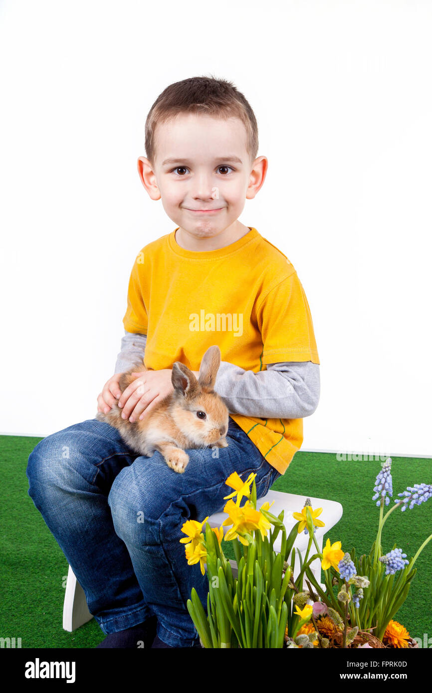 Young boy with colorful rabbit and spring flower on white background. Stock Photo