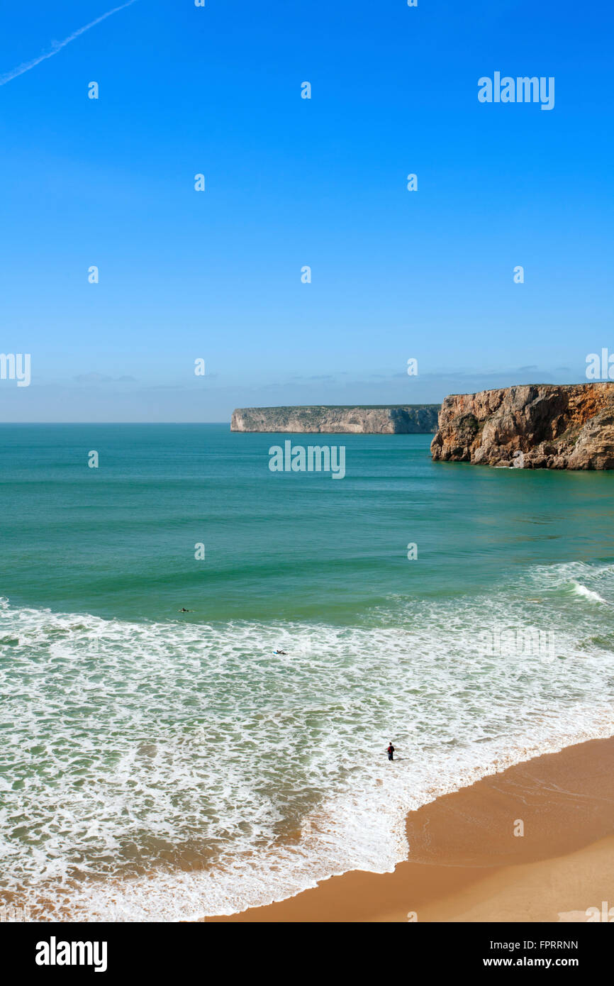Portugal, Algarve, Vila do Bispo, Sagres, Beliche beach, distant view of surfers, cliffs and Atlantic ocean, unspoilt beach, copy space, blue sky Stock Photo