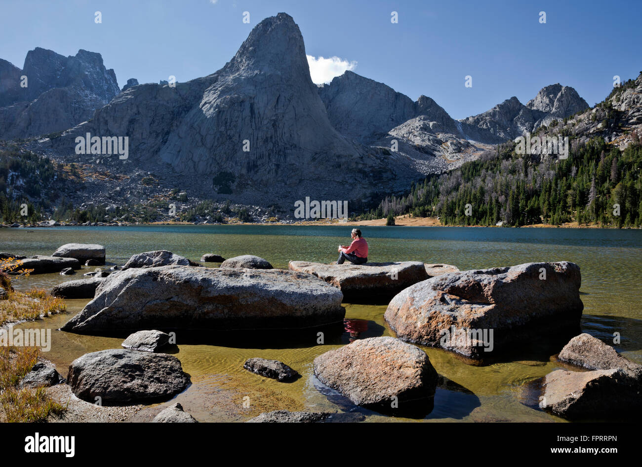 WY01342-00...WYOMING - Hiker relaxing on the shores of Lonesome Lake in the Cirque of Towers area of the Wind River Range. Stock Photo