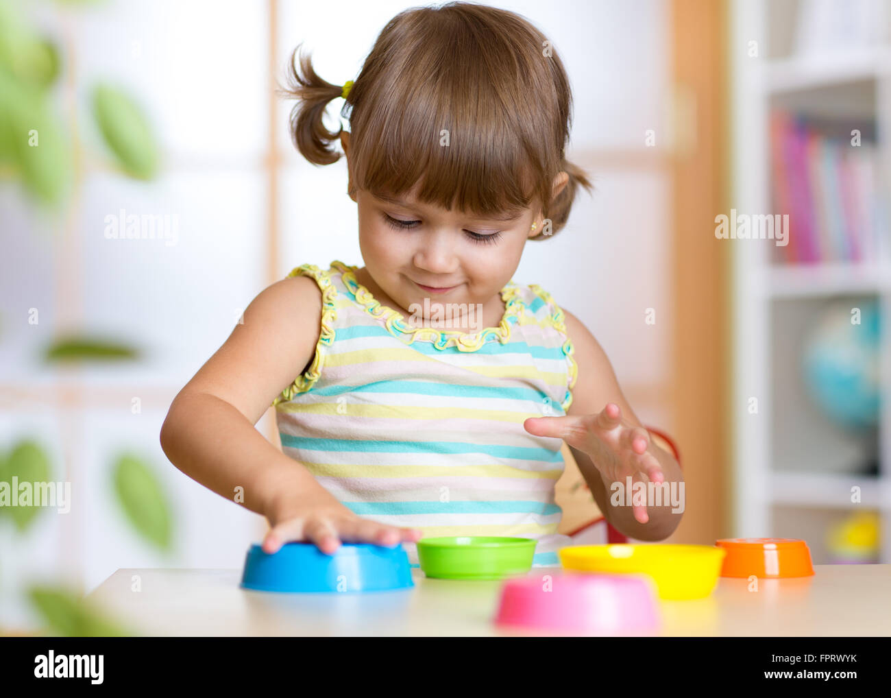 Adorable little girl playing with cup toys, smiling Stock Photo - Alamy
