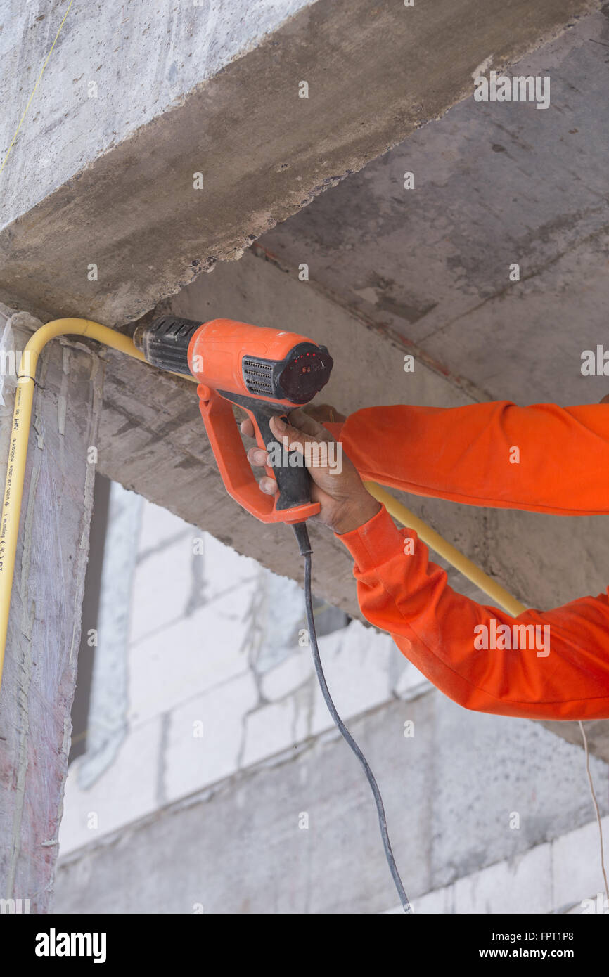 Hand of worker use a heat gun to bending electric PVC pipe Stock Photo