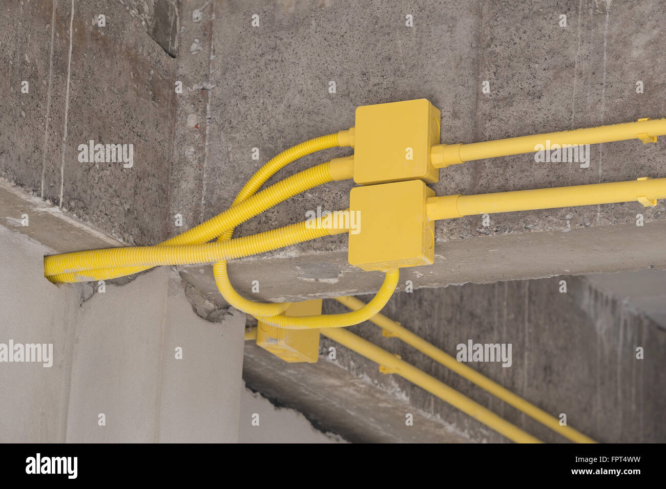 yellow PVC pipes for electrical boxes and wires buried on concrete wall at construction site