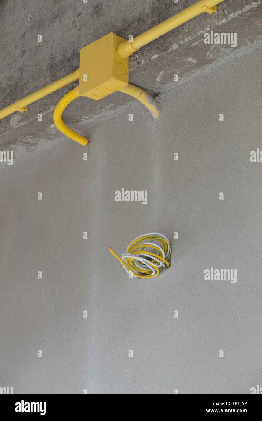 yellow PVC pipes for electrical boxes and wires buried on concrete wall at construction site