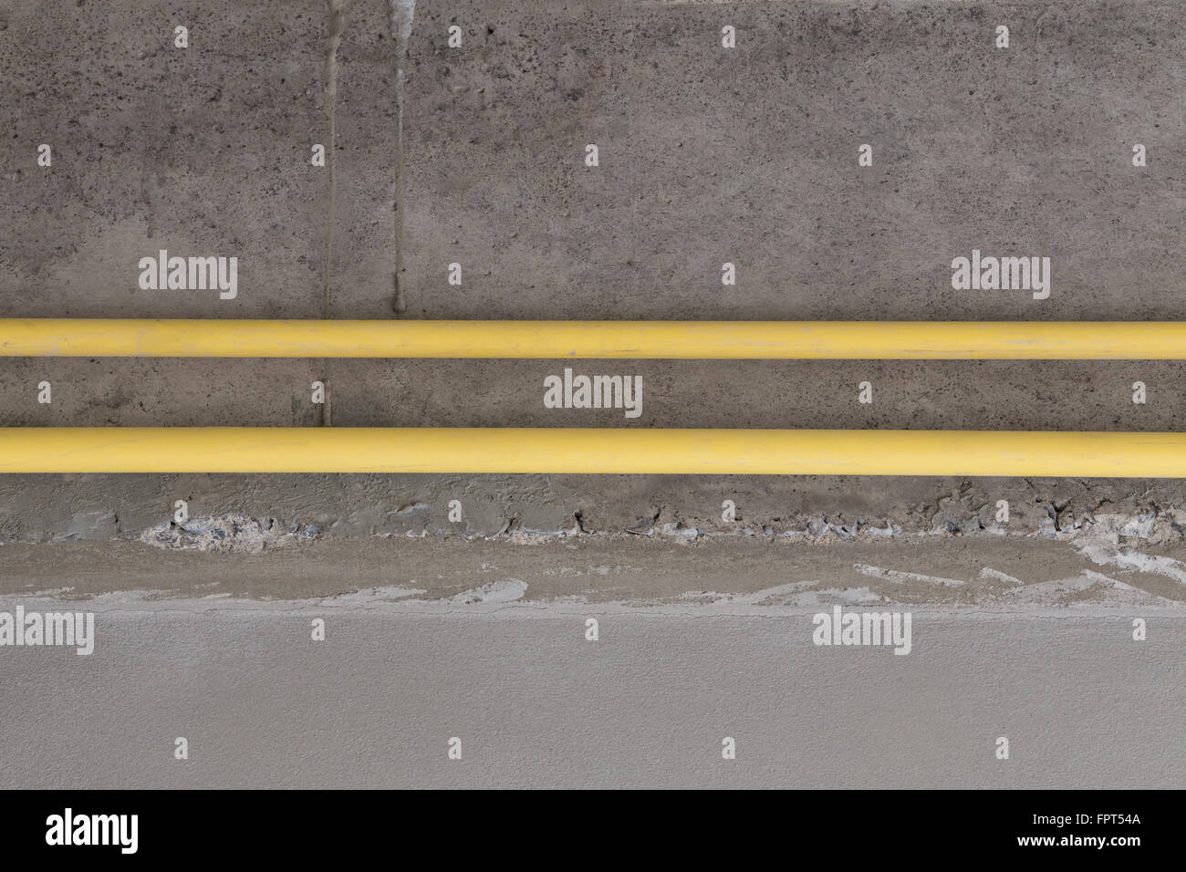 yellow PVC pipes for electrical boxes and wires buried on concrete wall at construction site