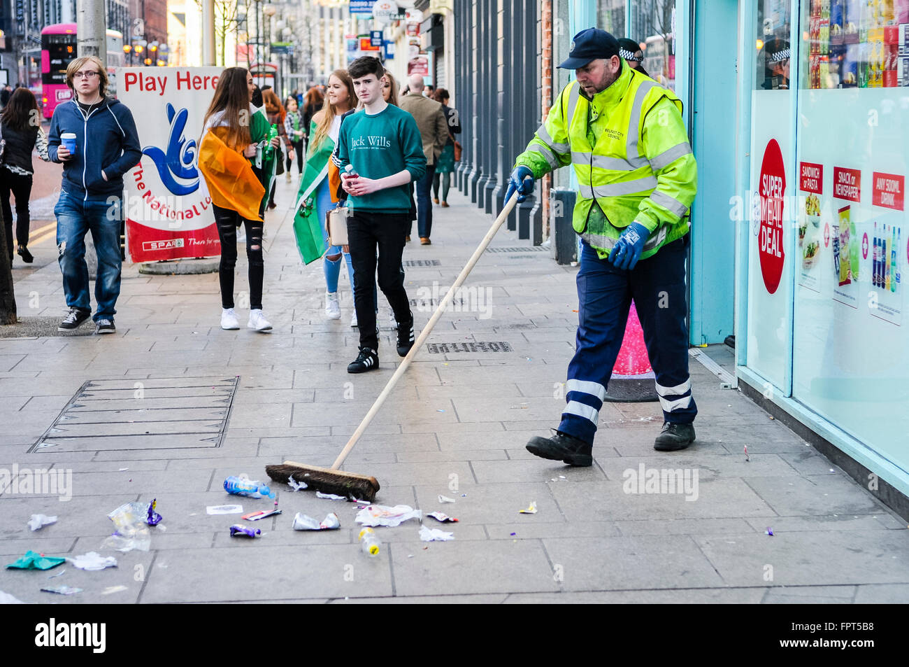 A council worker clears footpaths of a large amount of litter from a footpath after a large crowd has dispersed. Stock Photo