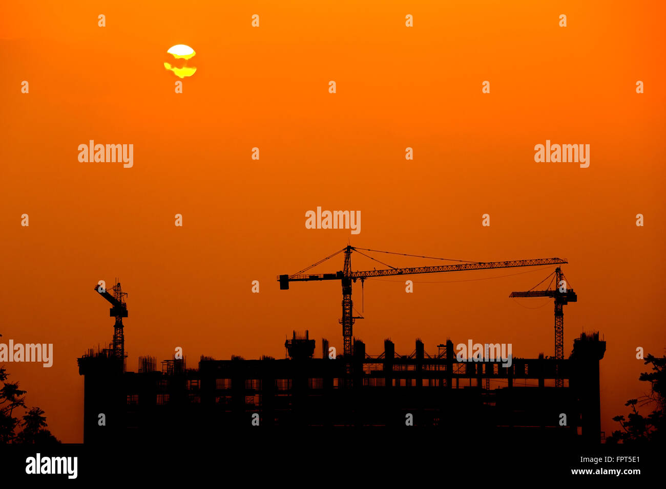 Silhouette of tower crane on a building construction site at sunset ...