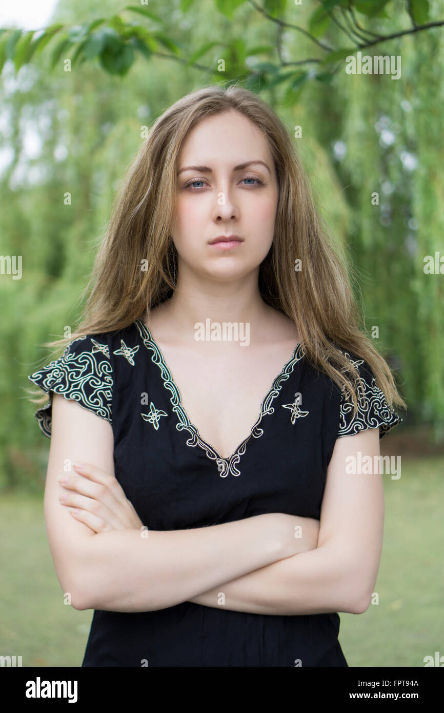 Serious young woman arms folded outdoors Stock Photo