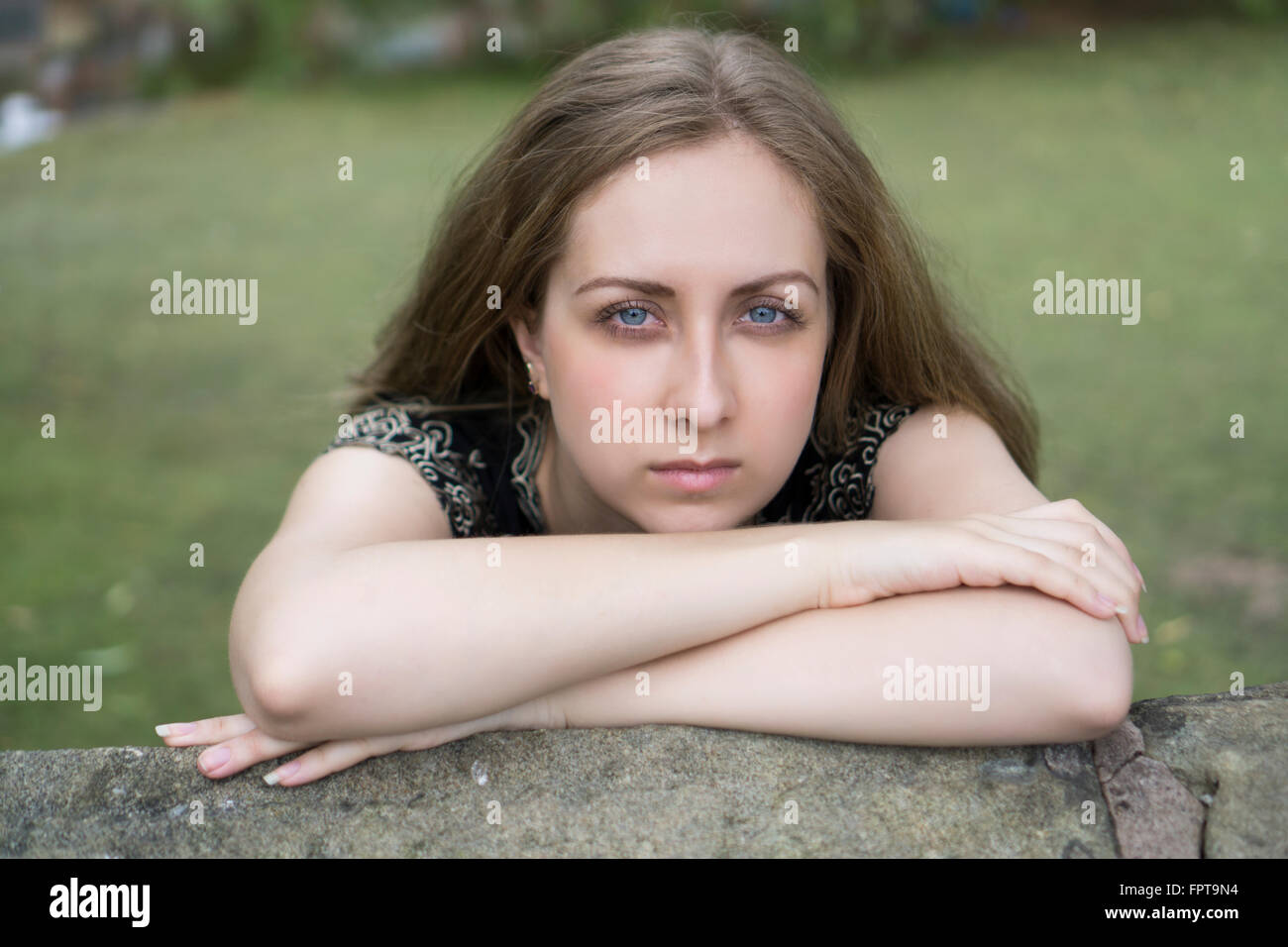 Serious young woman leaning on her arms outdoors Stock Photo