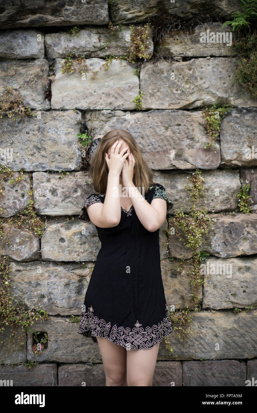 Young woman hiding face with hands outdoors Stock Photo