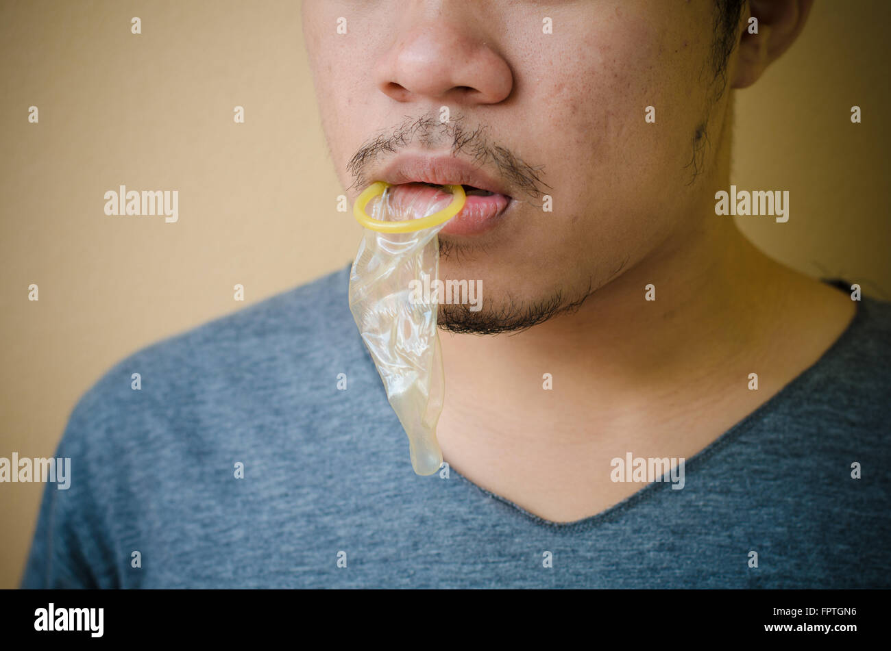 mouth of a young man licking a condom Stock Photo