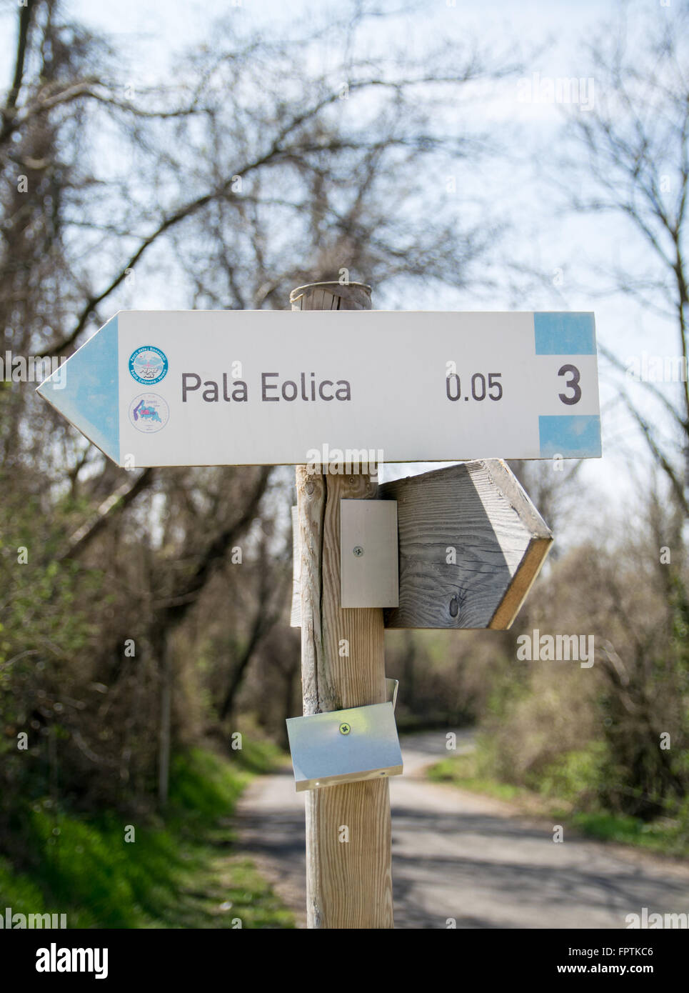 Wooden road sign indicating the direction to a wind farm. Stock Photo