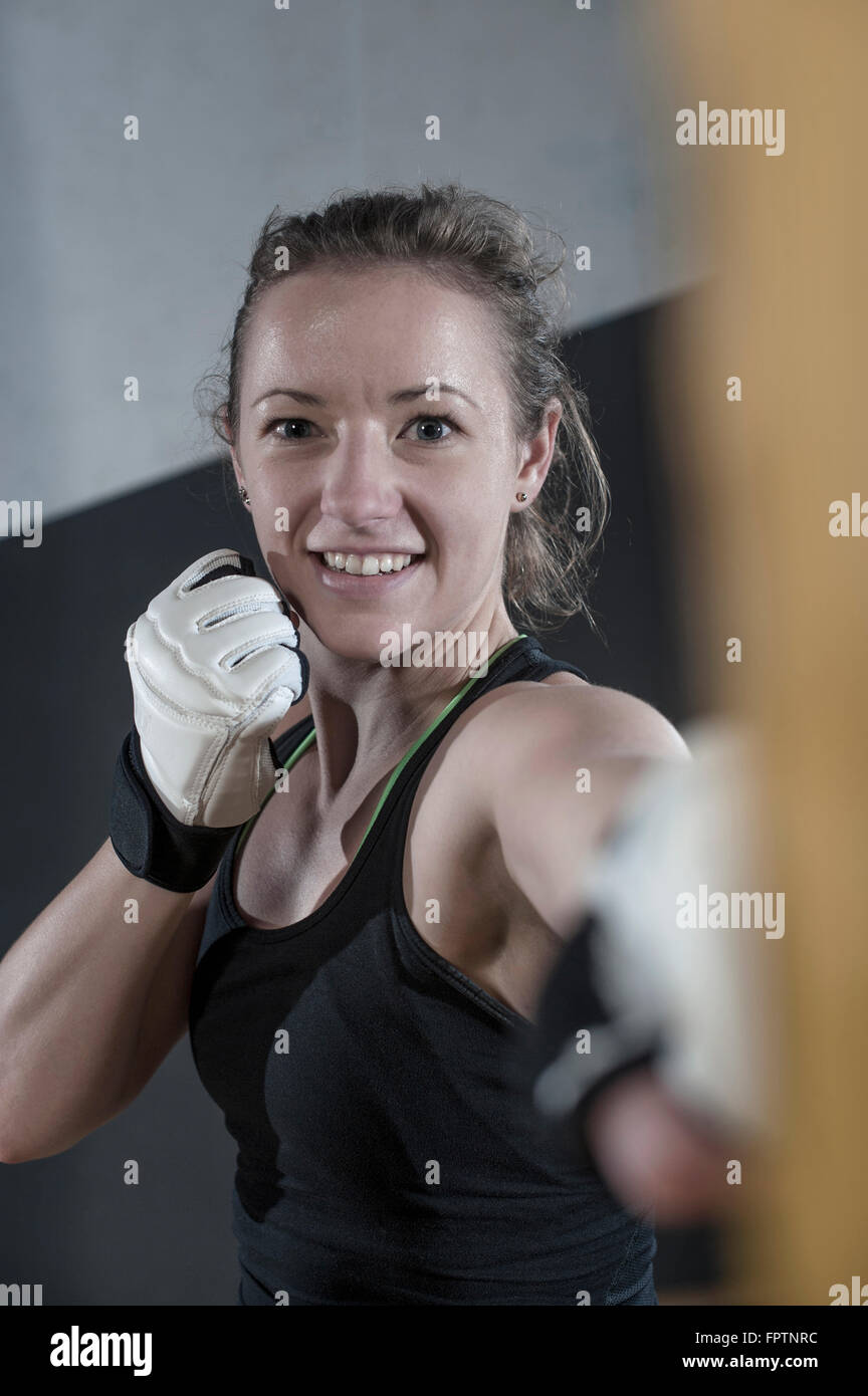 Young woman doing strength training by punching on punch bag in the gym, Bavaria, Germany Stock Photo