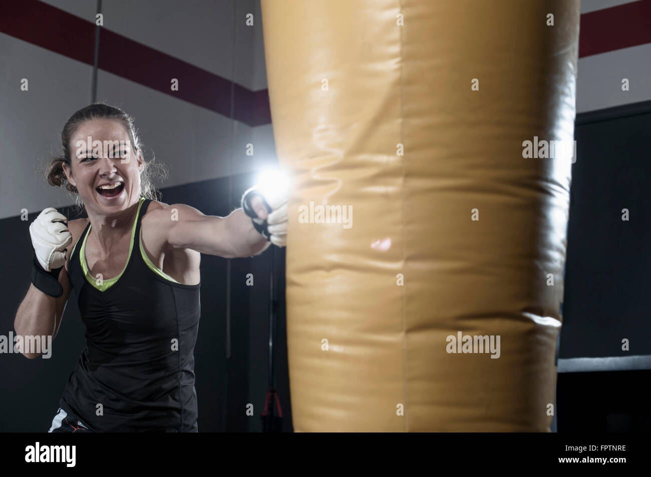 Sportswoman doing strength training by punching on punch bag in the gym, Bavaria, Germany Stock Photo