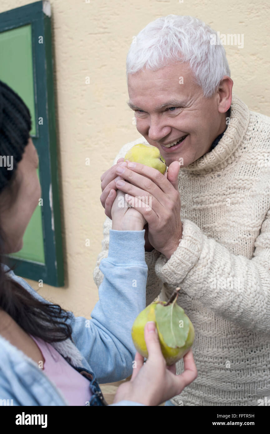 Female shop assistant gives quince to client for smelling, Bavaria, Germany Stock Photo