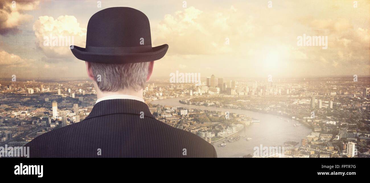 Businessman with bowler hat looking at financial city skyline concept for finance, investment, career and opportunity Stock Photo