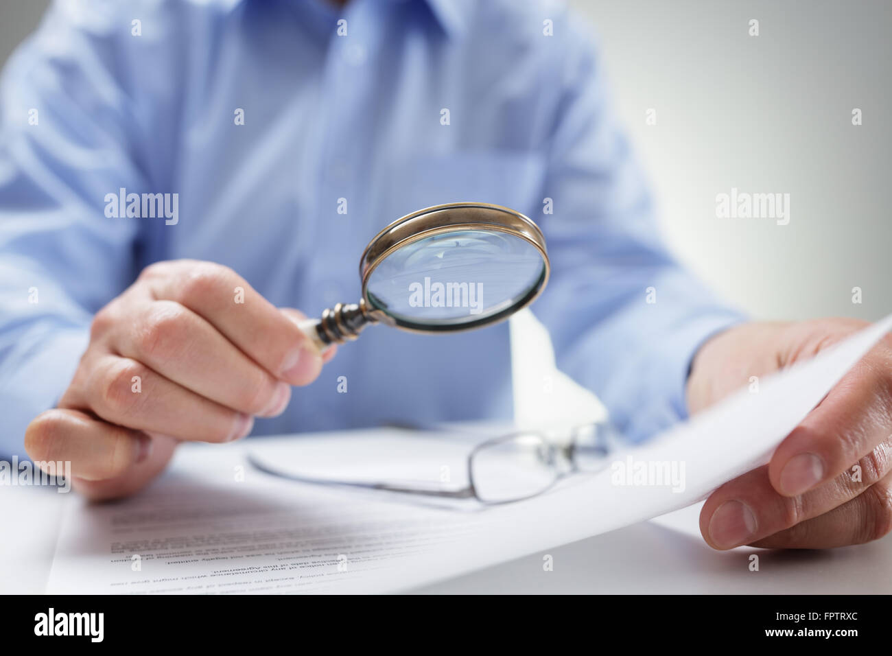 Businessman reading documents with magnifying glass Stock Photo