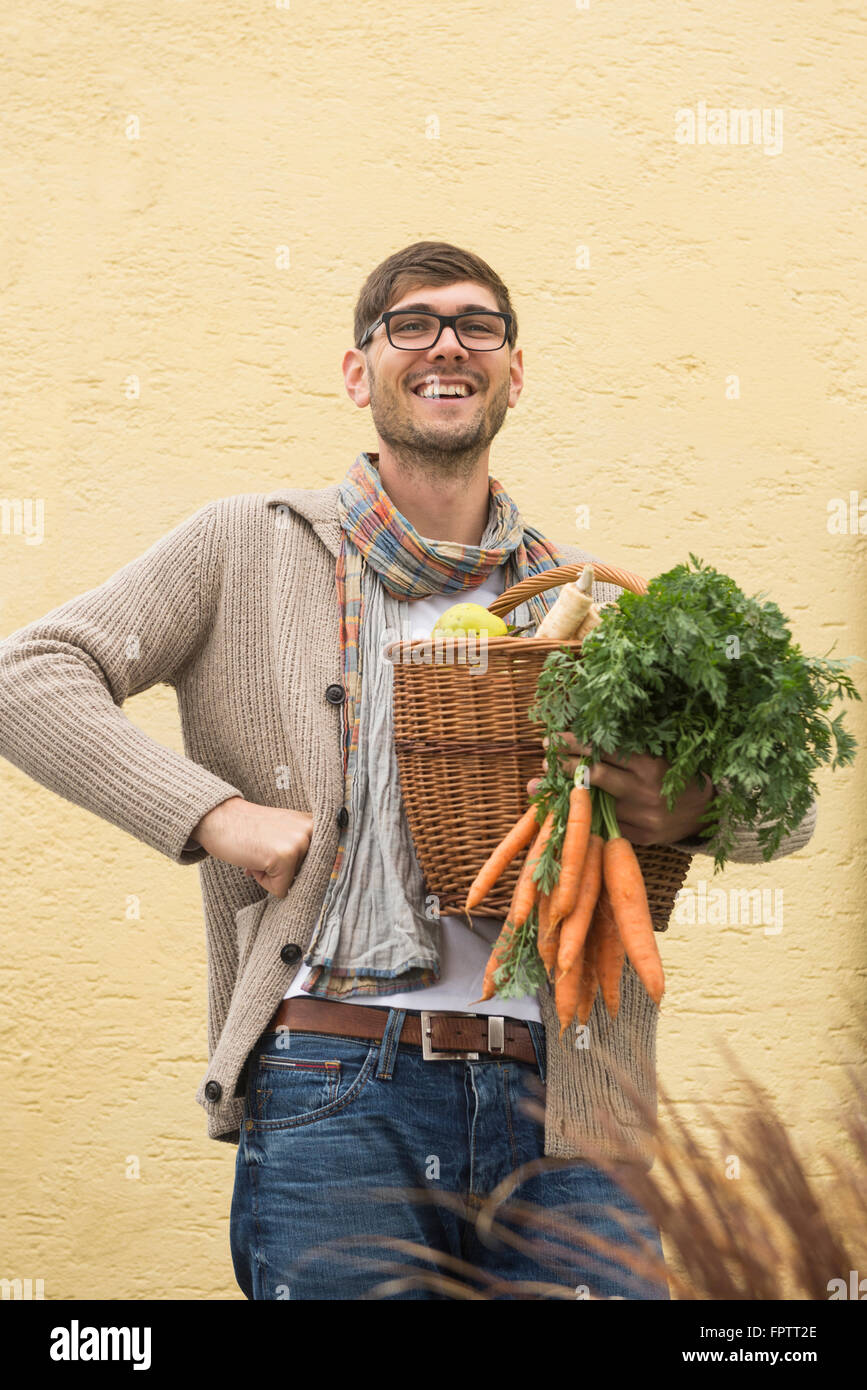 Portrait of a mid adult man holding basket full of vegetables and smiling, Bavaria, Germany Stock Photo
