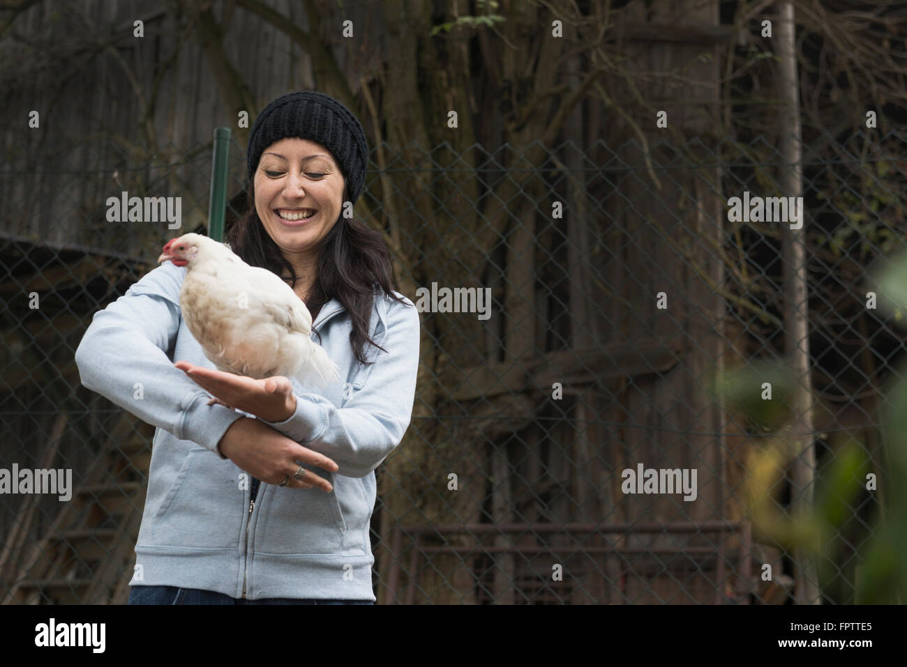 Farmer woman with white chicken bird and smiling in farm, Bavaria, Germany Stock Photo