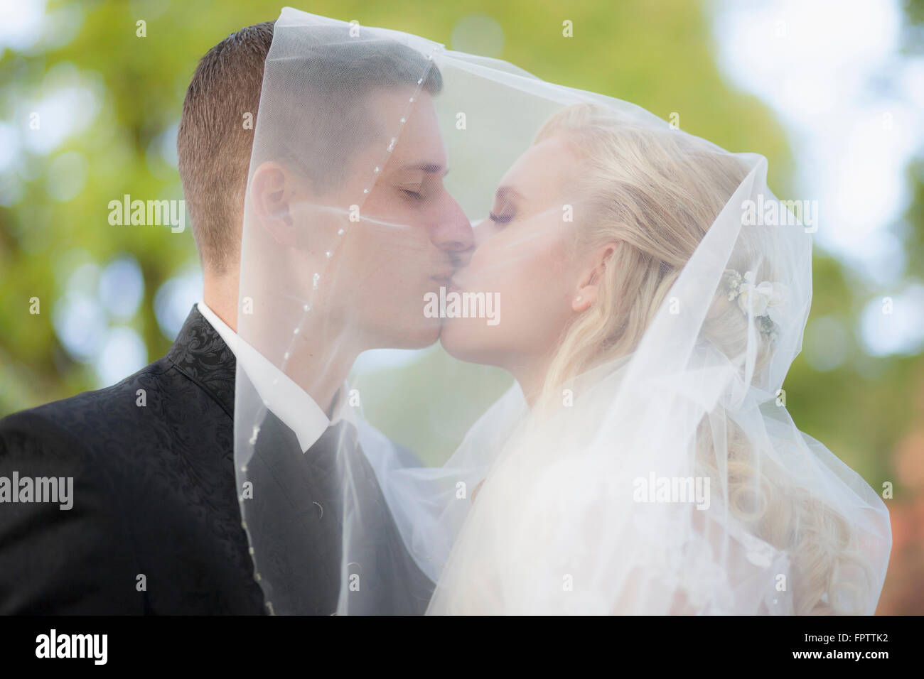 Close-up of a bride and groom kissing under veil, Ammersee, Upper Bavaria, Bavaria, Germany Stock Photo