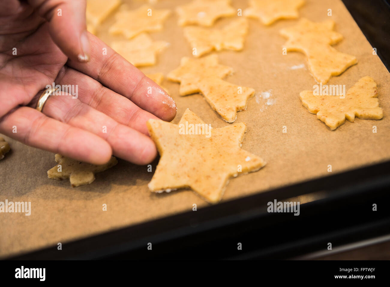 Close-up of a man placing star shaped cookies on baking sheet in a baking tray, Munich, Bavaria, Germany Stock Photo