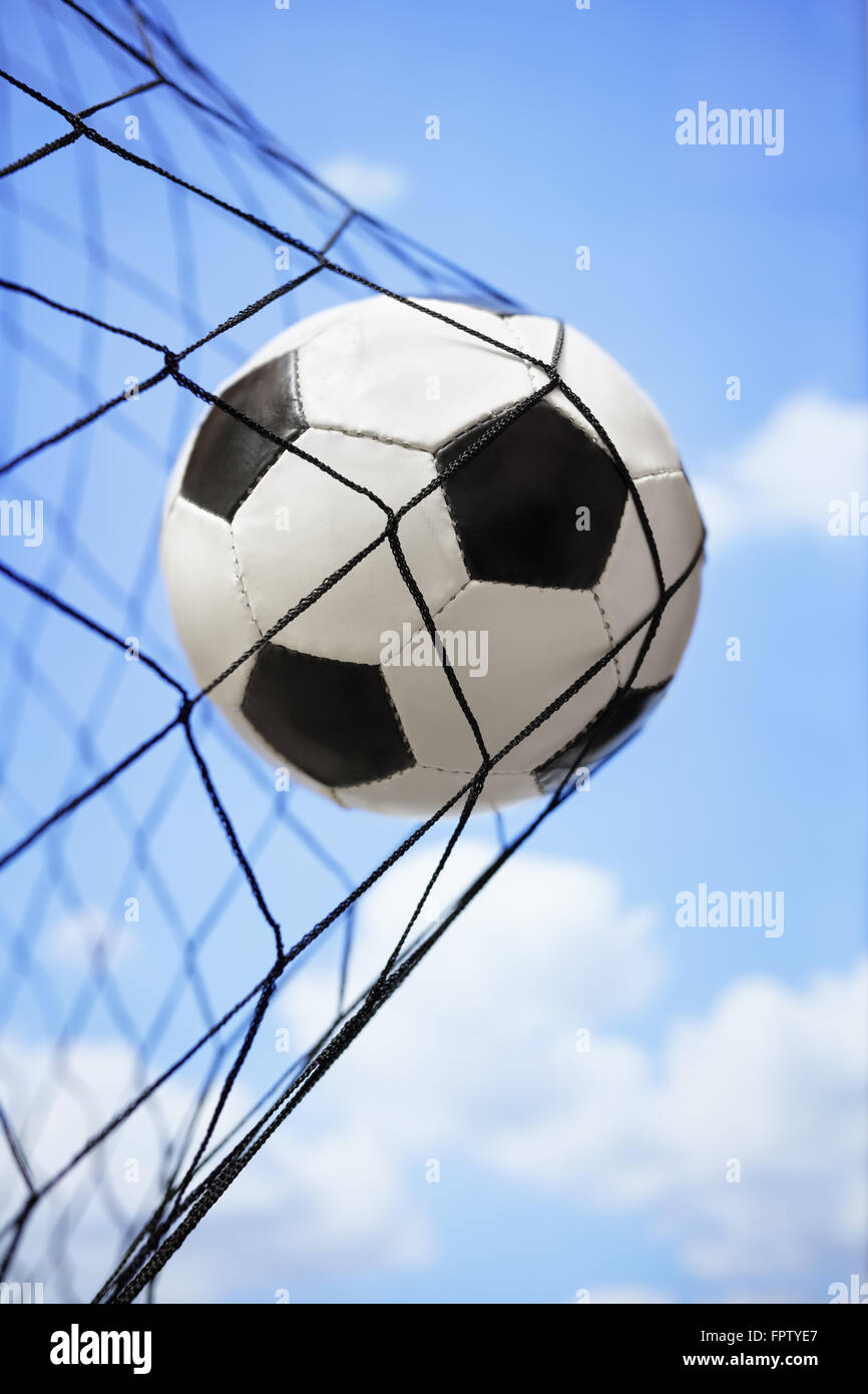 Football soccer ball in back of the net concept for goal, scoring, winning and team competition Stock Photo
